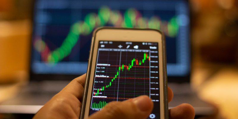 Image showing a trading platform on a laptop screen and mobile phone screen